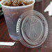 A Solo clear plastic lid with a straw slot on a plastic cup of ice.