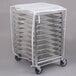 A metal sheet pan rack with white plastic cover and metal trays on it.