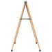 An Aarco oak A-frame sign board with a white marker board on a wooden easel with metal stand.