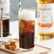 A glass of brown liquid with Monin Salted Caramel Flavoring and a straw.