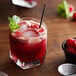 A glass of Monin raspberry drink with ice and raspberries.