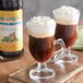 Two glasses of coffee with Monin Sugar Free Irish Cream syrup and whipped cream on top.