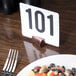 An American Metalcraft hammered copper cylinder table card holder with a number in it on a plate of food.