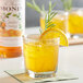 A glass of Monin orange juice with ice and a slice of orange.