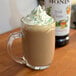 A glass mug of coffee with Monin Irish Cream syrup and whipped cream.