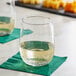 Two Acopa stemless wine glasses of white wine on a green napkin.