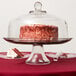 An Anchor Hocking glass cake dome over a cake on a glass stand.