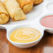 An American Metalcraft porcelain plate with egg rolls and dipping sauces in the compartments.