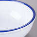 A white Cal-Mil melamine bowl with a blue rim.