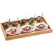 A Madera rustic pine serving tray with four dishes of food on a white surface.
