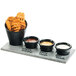 A Cal-Mil faux cement tray with small bowls of dipping sauces and fries on a table.