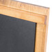 A wooden Cal-Mil Madera chalkboard stand on a table with a black chalkboard.