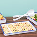 A white Cal-Mil melamine tray with a blue rim holding a variety of food.