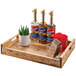 A Cal-Mil wood serving tray holding bottles of liquid and a potted plant.