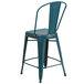 A distressed teal metal counter height stool with a vertical slat back.