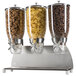 A Cal-Mil stainless steel cereal dispenser with three glass containers full of cereal.