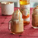 A glass mug of iced coffee with whipped cream and Monin Pumpkin Pie Syrup.