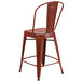 A red metal restaurant bar stool with a backrest.