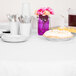 A table set with white Creative Converting table cover, plates, and utensils.