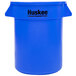 A blue plastic Continental Huskee trash can with black text reading "Huskee" on the side.