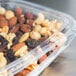 A Dart Clear plastic container filled with nuts and raisins.