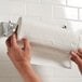 A hand holding a roll of Elegant 2-Ply paper towels.
