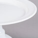 An Elite Global Solutions white melamine plate stand with a pedestal holding a white round plate.