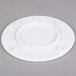 A white round Elite Global Solutions melamine plate on a pedestal with a round edge.