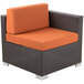 A BFM Seating Aruba outdoor wicker armchair with orange cushions.