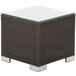 A BFM Seating Aruba wicker end table with glass top on an outdoor patio.