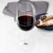A Libbey Vina tall wine glass filled with red wine on a table with pastries.