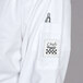 A Chef Revival Cuisinier white long sleeve chef coat with a pocket and pen inside.