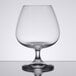 A Spiegelau Soiree cognac glass on a table with clear liquid inside.