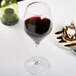 A close-up of a Spiegelau Adina Prestige Bordeaux wine glass filled with red wine on a table.