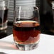 A Spiegelau Vino Grande shot glass filled with brown liquid on a table.