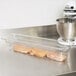 A Cambro clear polycarbonate food pan filled with raw chicken.