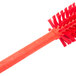 A Carlisle red plastic brush with bristles.