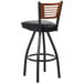 A BFM Seating black metal bar stool with a cherry wooden back and black vinyl seat.