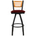 A BFM Seating bar stool with a burgundy vinyl swivel seat and black metal frame with a natural wood back.
