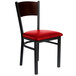 A BFM Seating black metal side chair with a red vinyl seat and walnut finish wooden back.