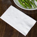A plate of green beans and a white Response Eco-Friendly Dinner napkin on a table.