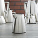 A group of Vollrath stainless steel open creamers on a table.