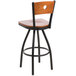 A BFM Seating black metal bar stool with a cherry wooden back and swivel seat.