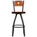 A BFM Seating black metal bar stool with a cherry wooden back and swivel seat.