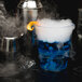 A WNA Comet clear plastic rocks glass filled with blue liquid with smoke coming out