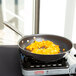 A Vollrath stainless steel frying pan with yellow food in it.