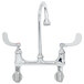 A T&S chrome wall mounted surgical sink faucet with 2 wrist action handles and a gooseneck spout.