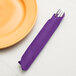 A fork and knife wrapped in a Creative Converting amethyst purple dinner napkin.