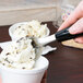 A Tablecraft stainless steel ice cream spade scooping ice cream into a cup.