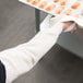 A person's arm wearing a white Cordova terry cloth sleeve holding a tray of food.